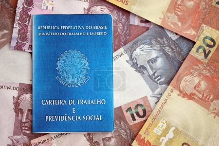 Photo for Brazilian work card and social security blue book and reais money bills close up - Royalty Free Image