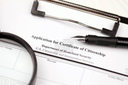 Foto de N-600 Solicitud de Certificado de Ciudadanía formulario en blanco en la tableta A4 se encuentra en la mesa de oficina con lápiz y lupa de cerca - Imagen libre de derechos