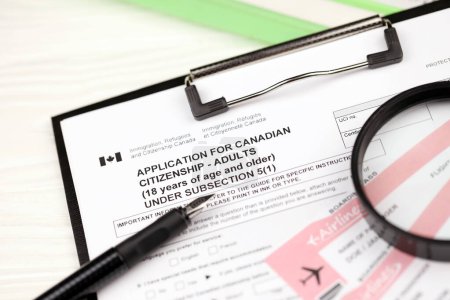 Téléchargez les photos : Demande de citoyenneté canadienne pour les adultes sur tablette A4 se trouve sur la table de bureau avec stylo et loupe gros plan - en image libre de droit