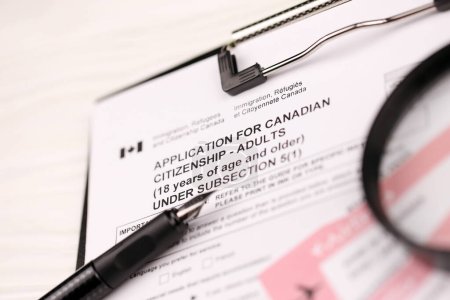 Téléchargez les photos : Demande de citoyenneté canadienne pour les adultes sur tablette A4 se trouve sur la table de bureau avec stylo et loupe gros plan - en image libre de droit