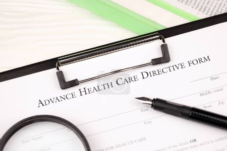 Directive préalable sur les soins de santé formulaire vierge sur tablette A4 se trouve sur la table de bureau avec stylo et loupe gros plan