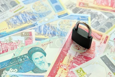 Photo for Small padlock lies on pile of iranian money close up. Sanctions, ban or embargo concept - Royalty Free Image