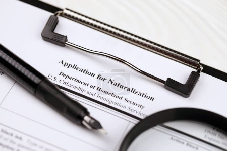 Photo for N-400 Application for Naturalization blank form on A4 tablet lies on office table with pen and magnifying glass close up - Royalty Free Image