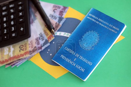Photo for Brazilian work card and social security blue book and reais money bills with calculator and pen on flag of Federative Republic of Brazil close up - Royalty Free Image
