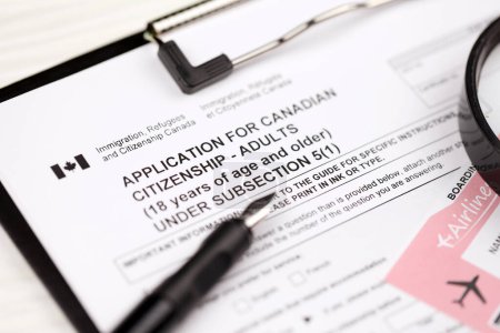 Photo for Application for Canadian citizenship for adults on A4 tablet lies on office table with pen and magnifying glass close up - Royalty Free Image