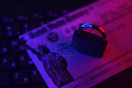 Téléchargez les photos : États-Unis Trésor chèque de remboursement ou de stimulus facture avec petit cadenas sur clavier d'ordinateur fermer - en image libre de droit
