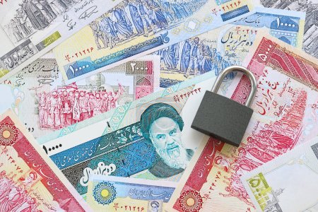 Photo for Small padlock lies on pile of iranian money close up. Sanctions, ban or embargo concept - Royalty Free Image