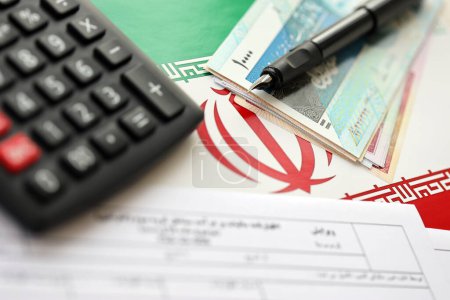 Formulario de declaración anual de impuestos iraníes F20-25-006 listo para llenar en la mesa con pluma, calculadora y dinero iraní en la bandera de cerca