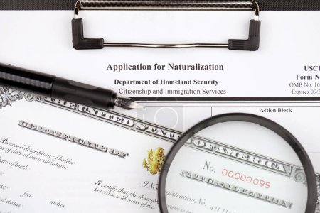Foto de N-400 Solicitud de naturalización y certificado de naturalización en la tableta A4 se encuentra en la mesa de oficina con lápiz y lupa de cerca - Imagen libre de derechos