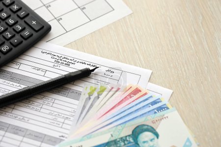 Formulaire de déclaration de revenus annuelle iranienne F20-25-006 prêt à remplir sur table avec stylo, calculatrice et argent roumain close up