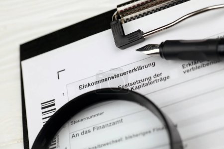 Photo for German annual income tax return declaration form blank on A4 tablet lies on office table with pen and magnifying glass close up - Royalty Free Image
