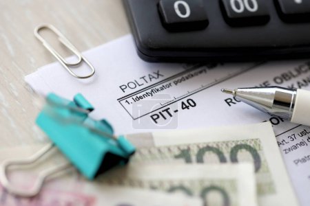 Calcul annuel de l'impôt sur le revenu obtenu par le contribuable, formulaires d'impôt PIT-40 sur table comptable avec plume et polissage zloty billets fermer