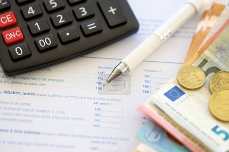 Téléchargez les photos : Remplir le formulaire d'impôt français avec la calculatrice, le stylo et les billets en euros fermer. Période et délai de paiement des impôts - en image libre de droit
