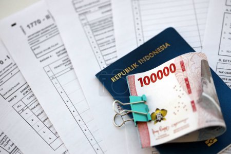 Téléchargez les photos : Formulaires fiscaux indonésiens 1770 Déclaration de revenus des particuliers et argent avec passeport sur la table close up - en image libre de droit