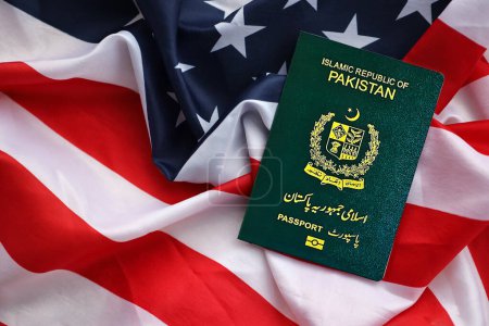 Grüner Pass der Islamischen Republik Pakistan auf dem Hintergrund der Nationalflagge der Vereinigten Staaten in Großaufnahme. Tourismus- und Diplomatie-Konzept