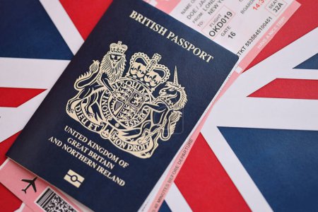Blauer britischer Pass mit Flugtickets vor dem Hintergrund der Nationalflagge in Großaufnahme. Tourismus- und Reisekonzept