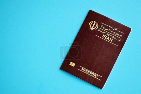 Red Islamic Republic of Iran passport on blue background close up. Tourism and citizenship concept