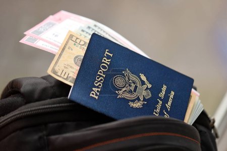 Blue United States of America passport with money and airline tickets on touristic backpack close up. Tourism and travel concept