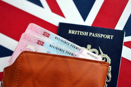Residence Permit BRP card and British Passport of United Kingdom on Union Jack flag close up