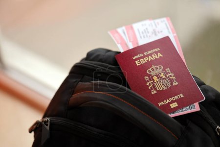 Passeport espagnol rouge de l'Union européenne avec billets d'avion sur le sac à dos touristique de près. Tourisme et concept de voyage