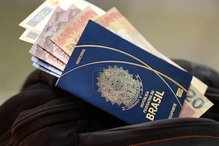 Blauer brasilianischer Pass mit Geld und Flugtickets auf Touristenrucksack aus nächster Nähe. Tourismus- und Reisekonzept