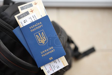 Dos pasaportes biométricos ucranianos con billetes de avión en la mochila turística negra de cerca