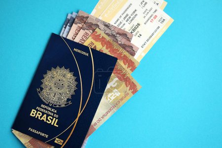 Passeport brésilien bleu avec de l'argent et des billets d'avion sur fond bleu fermer. Tourisme et concept de voyage