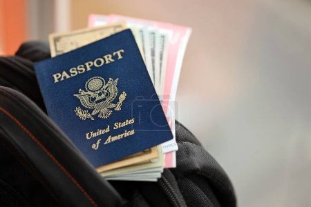 Blauer Reisepass der Vereinigten Staaten von Amerika mit Geld und Flugtickets auf Touristenrucksack aus nächster Nähe. Tourismus- und Reisekonzept
