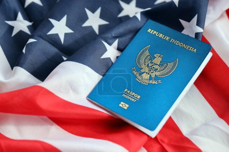 Téléchargez les photos : Passeport de la République bleue d'Indonésie sur fond de drapeau national des États-Unis fermer. Tourisme et diplomatie concept - en image libre de droit