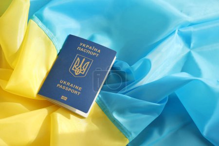 One Ukrainian biometrical passport on folded waving flag of Ukraine country close up