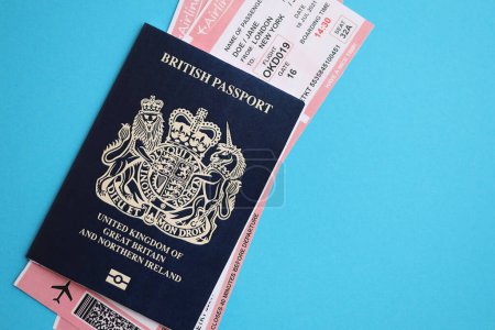 Blauer britischer Pass mit Flugtickets auf blauem Hintergrund in Großaufnahme. Tourismus- und Reisekonzept