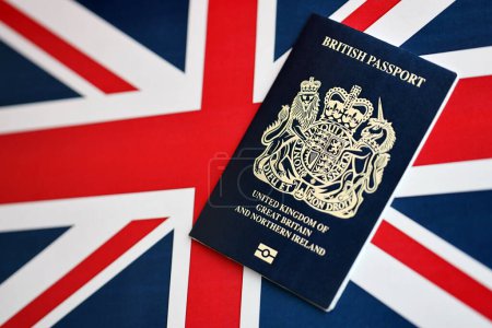 Blue British passport on national flag background close up. Tourism and citizenship concept