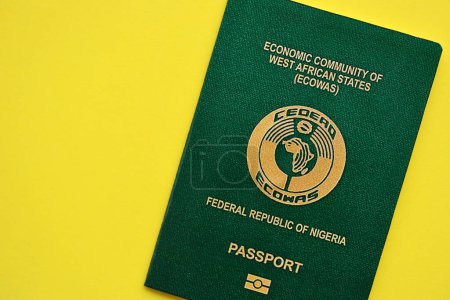 Green Nigerian passport on yellow background close up. Tourism and citizenship concept
