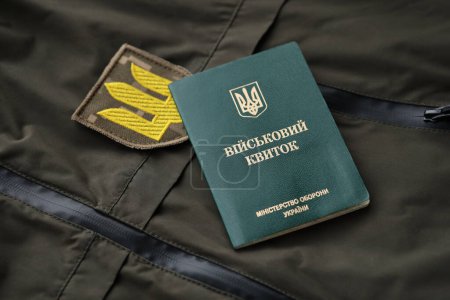 Militärmarke oder Armeeausweis liegt auf grüner ukrainischer Militäruniform drinnen in Großaufnahme