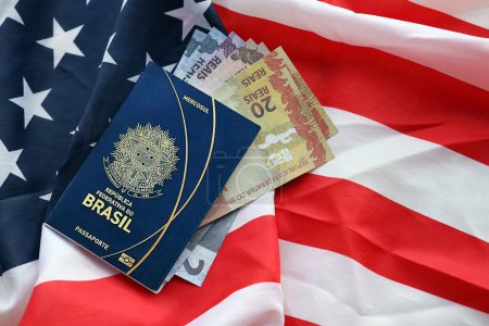 Blauer brasilianischer Pass und Geld auf dem Hintergrund der Nationalflagge der Vereinigten Staaten in Nahaufnahme. Tourismus- und Diplomatie-Konzept