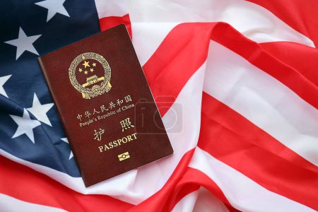 Red passport of People Republic of China on United States flag. PRC chinese passport on bright background close up