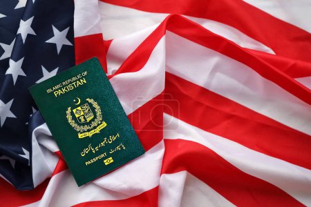 Grüner Pass der Islamischen Republik Pakistan auf dem Hintergrund der Nationalflagge der Vereinigten Staaten in Großaufnahme. Tourismus- und Diplomatie-Konzept