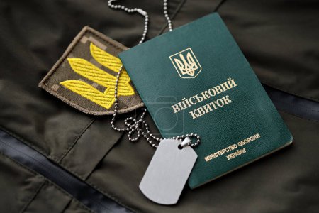 Téléchargez les photos : Jeton militaire ou billet d'identité de l'armée se trouve sur vert uniforme militaire ukrainien à l'intérieur fermer - en image libre de droit