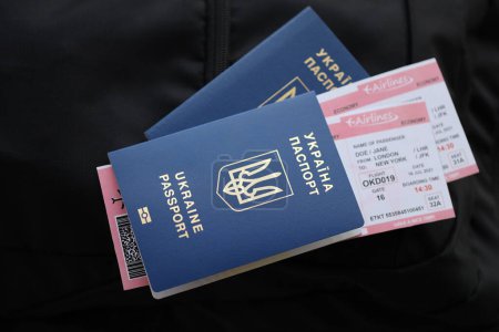Deux passeports biométriques ukrainiens avec billets d'avion sur sac à dos touristique noir de près