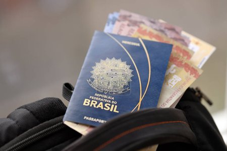 Pasaporte brasileño azul con billetes de avión y dinero en mochila turística de cerca. Concepto de turismo y viajes