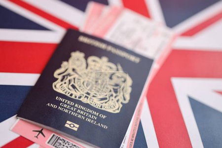 Passeport britannique bleu avec billets d'avion sur fond de drapeau national fermer. Tourisme et concept de voyage