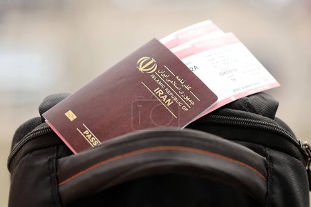 Roter Pass der Islamischen Republik Iran mit Flugtickets auf Touristenrucksack in Großaufnahme. Tourismus- und Reisekonzept