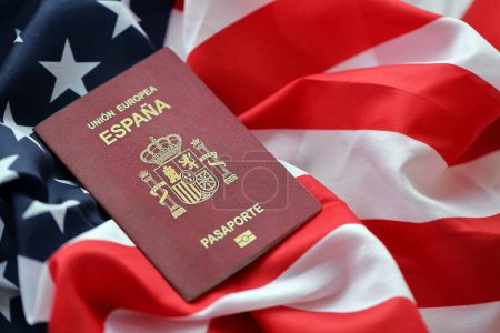 Pasaporte rojo español de la Unión Europea sobre fondo de la bandera nacional de los Estados Unidos de cerca. Concepto de turismo y diplomacia
