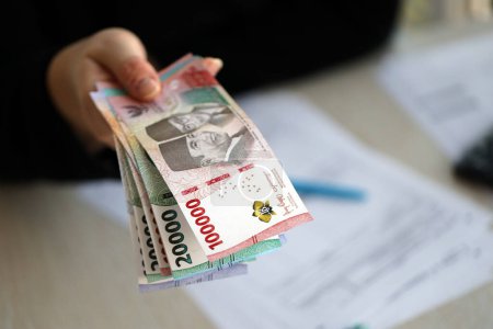 Female accountant hand give bunch of many indonesian rupiah money bills of new series close up