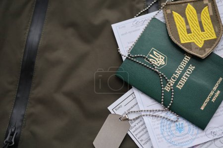 Foto de Boleto de identificación militar o militar con aviso de movilización se encuentra en uniforme militar ucraniano verde en el interior de cerca - Imagen libre de derechos
