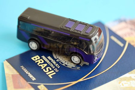 Blauer brasilianischer Pass mit Geld und kleinem Bus auf blauem Hintergrund in Großaufnahme. Tourismus- und Reisekonzept