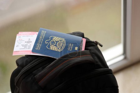Blue United Arab Emirates passport with airline tickets on touristic backpack close up. Tourism and travel concept
