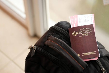 Roter Pass der Islamischen Republik Iran mit Flugtickets auf Touristenrucksack in Großaufnahme. Tourismus- und Reisekonzept