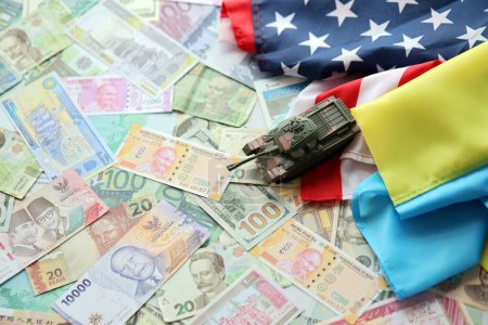 Réservoir de jouets sur le drapeau américain et le drapeau ukrainien sur de nombreux billets de différentes devises. Contexte du financement de la guerre et du soutien militaire entre les États-Unis et l'Ukraine