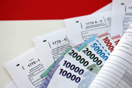Indonesische Steuerformulare 1770 Individuelle Einkommensteuererklärung und andere mit Geld auf dem Tisch in Großaufnahme